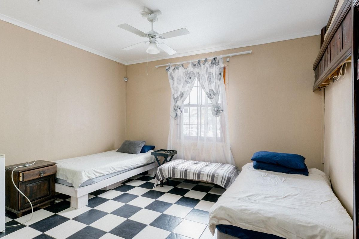 A bedroom featuring a checkerboard tiled floor, ceiling fan, and built-in wooden shelving unit.