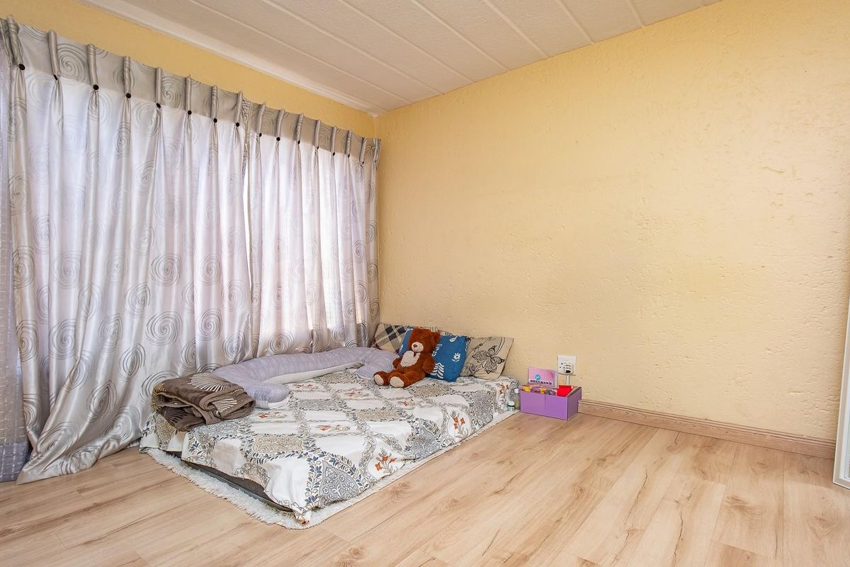 A bedroom featuring light wood-look laminate flooring and neutral wall tones, providing a simple and functional living space.