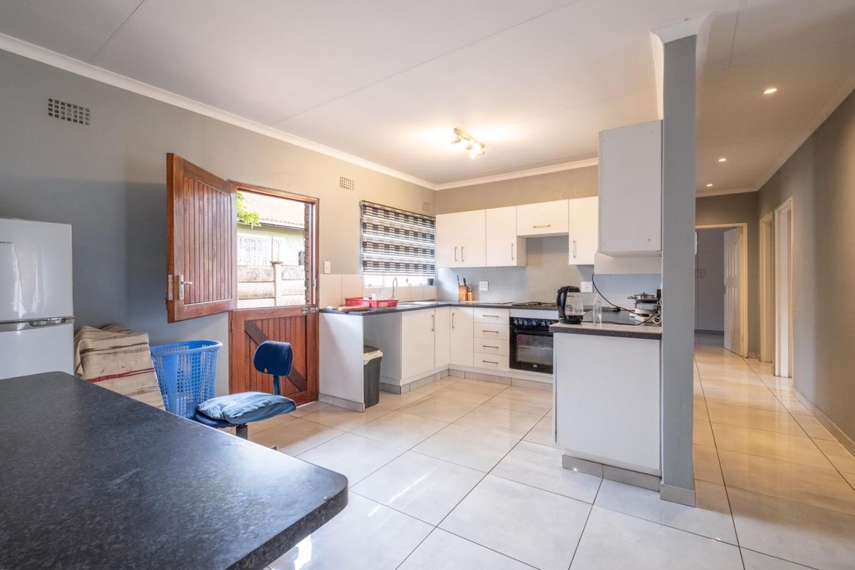 A functional kitchen featuring white cabinetry, built-in oven and hob, tiled flooring, and direct access to the exterior via a stable-style door.