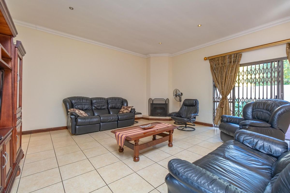 Spacious living room featuring tiled flooring, a corner fireplace, and sliding glass doors leading to the exterior with security gate.