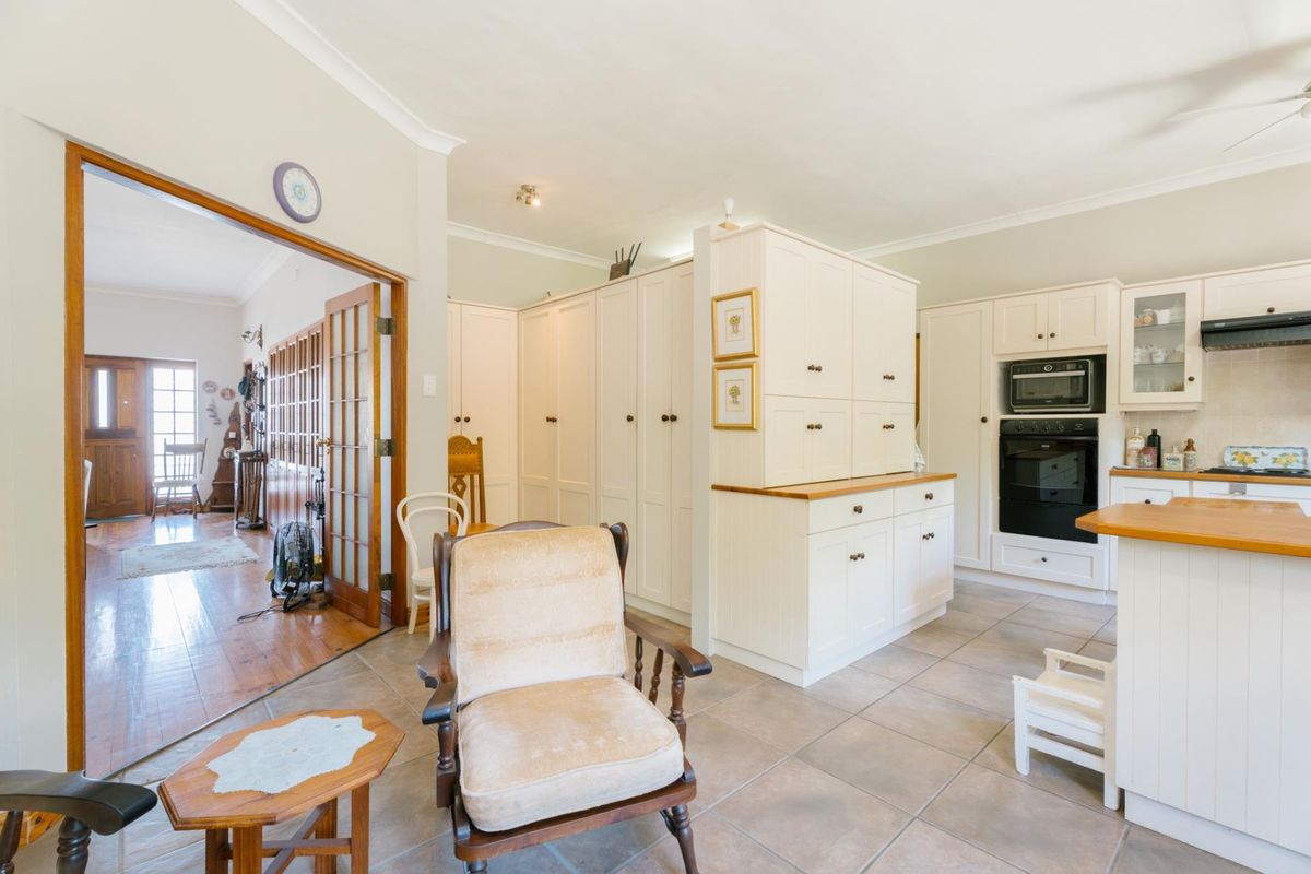 A bright kitchen featuring white cabinetry, built-in oven, microwave, and tiled flooring, with an open-plan layout connecting to the adjacent hallway.