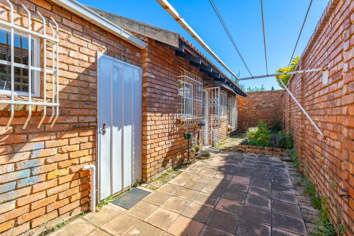 A private rear courtyard featuring exposed brick walls, paved flooring, and a fixed outdoor washing line, providing a functional utility space.