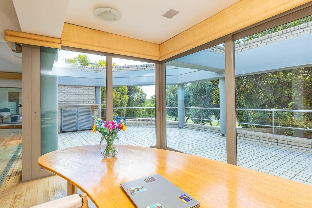 Spacious living area featuring large floor-to-ceiling glass sliding doors that open onto a covered patio with brick detailing and garden views.