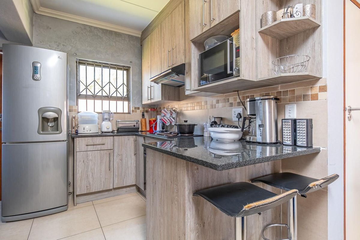 Compact kitchen featuring wood-look cabinetry, granite countertops, tiled backsplash, and built-in extractor fan, offering a functional workspace.