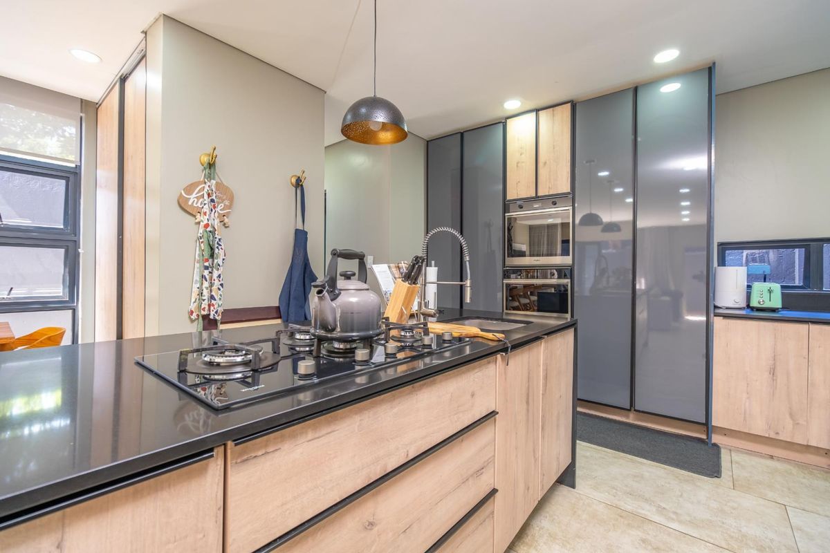 Modern kitchen featuring a central island with a built-in gas hob, sleek cabinetry, integrated oven, and high-quality finishes throughout.