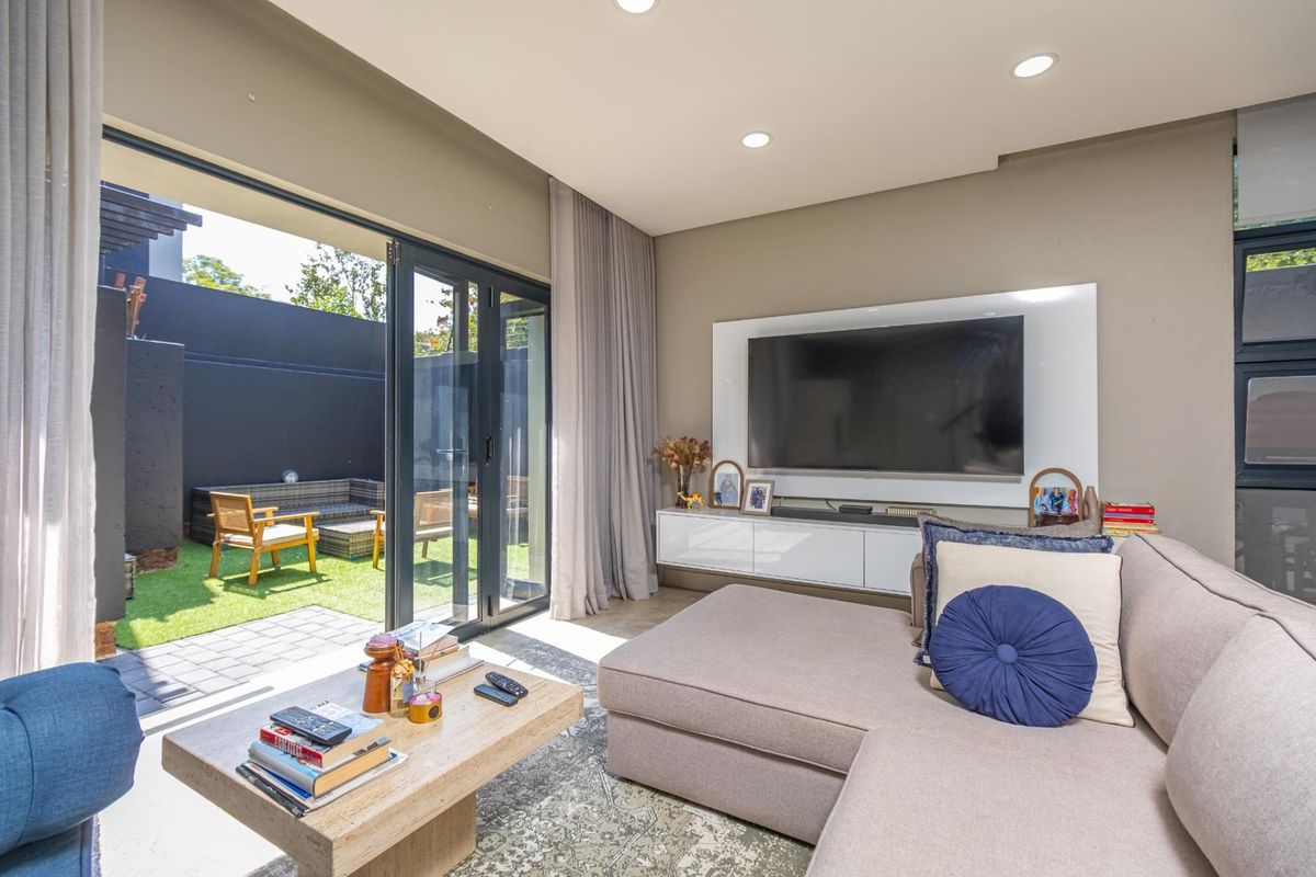 Modern living room featuring large sliding glass doors that open onto a private patio and garden area, creating a seamless indoor-outdoor flow.