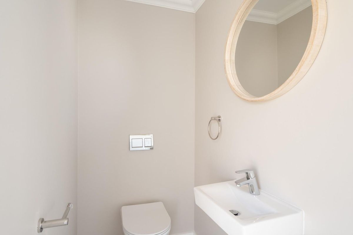 A modern guest bathroom featuring a wall-mounted toilet with a dual-flush plate and a sleek wall-hung basin with a chrome mixer tap.
