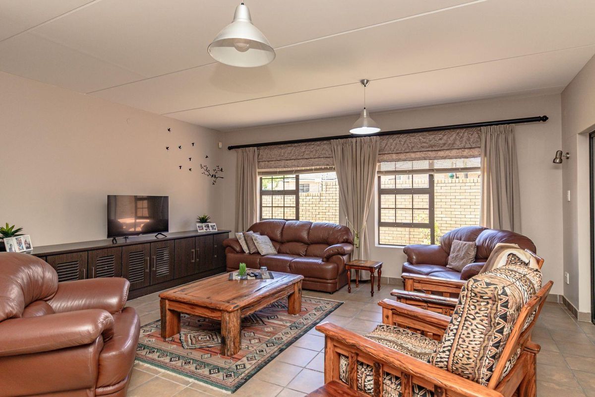 Spacious living room featuring tiled flooring, large windows with blinds, and sliding door access to the exterior.