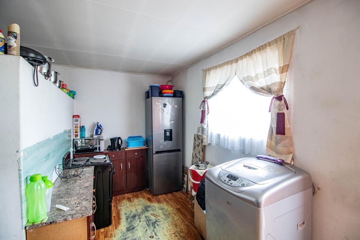 A compact kitchen and laundry area featuring laminate countertops, dark wood cabinetry, and space for essential appliances.