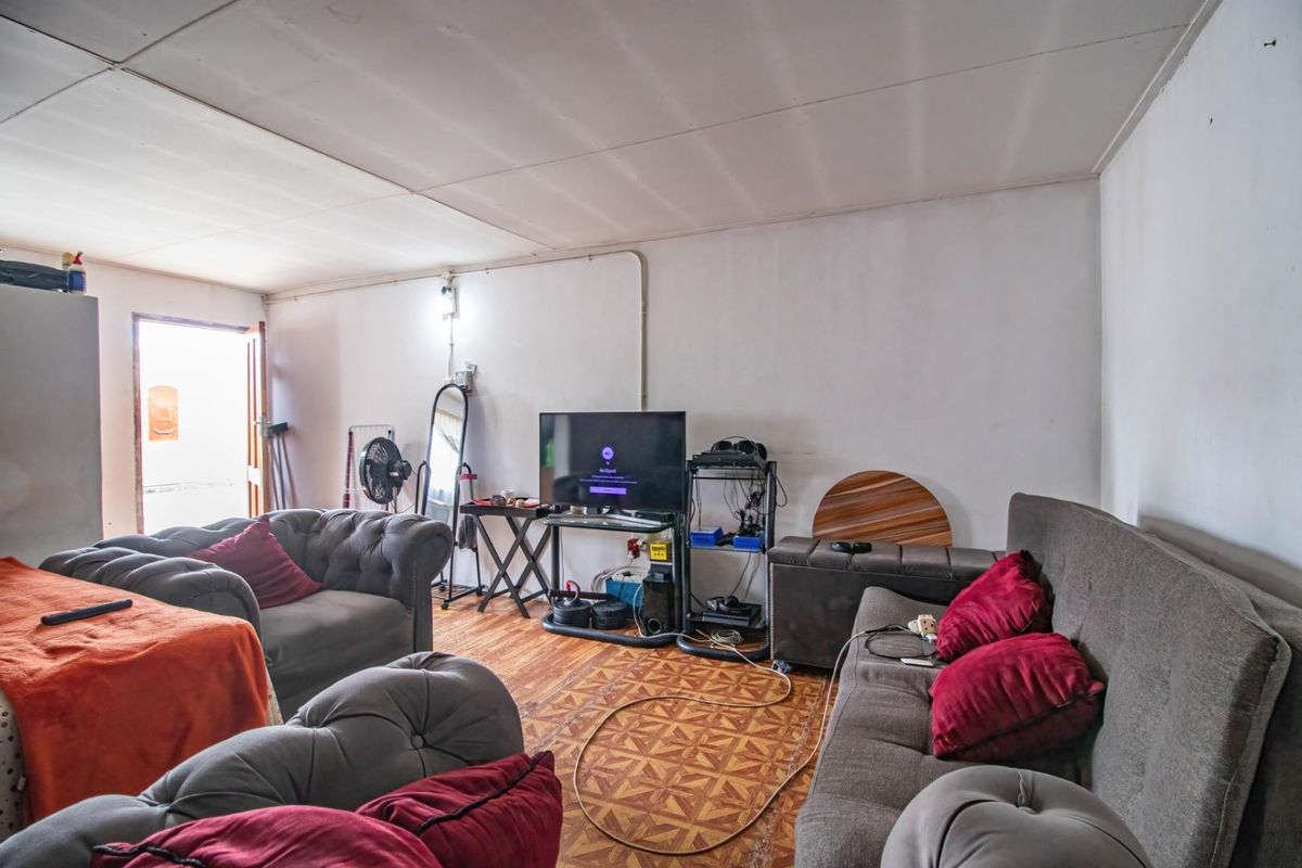 A living area featuring patterned floor tiles, surface-mounted electrical wiring, and direct access to an exterior space.