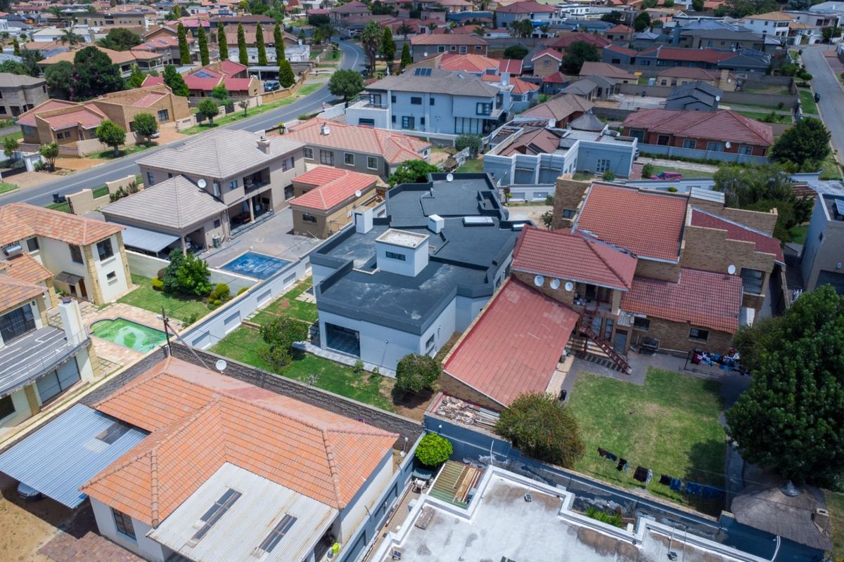 An aerial view of the residential property showing the roof structure, surrounding garden space, and the layout of the neighbouring suburban homes.