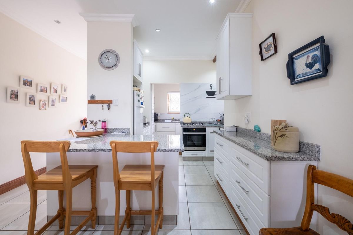 A well-maintained kitchen featuring white cabinetry, granite countertops, a breakfast bar, and built-in oven with gas hob.