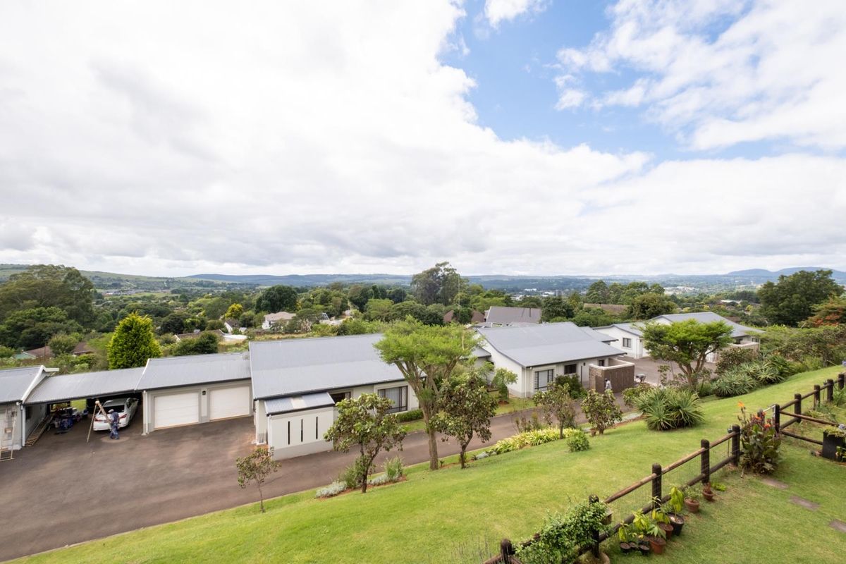 An elevated aerial view of the property complex featuring multiple residential units, paved driveways, garages, and expansive landscaped grounds with scenic valley views.