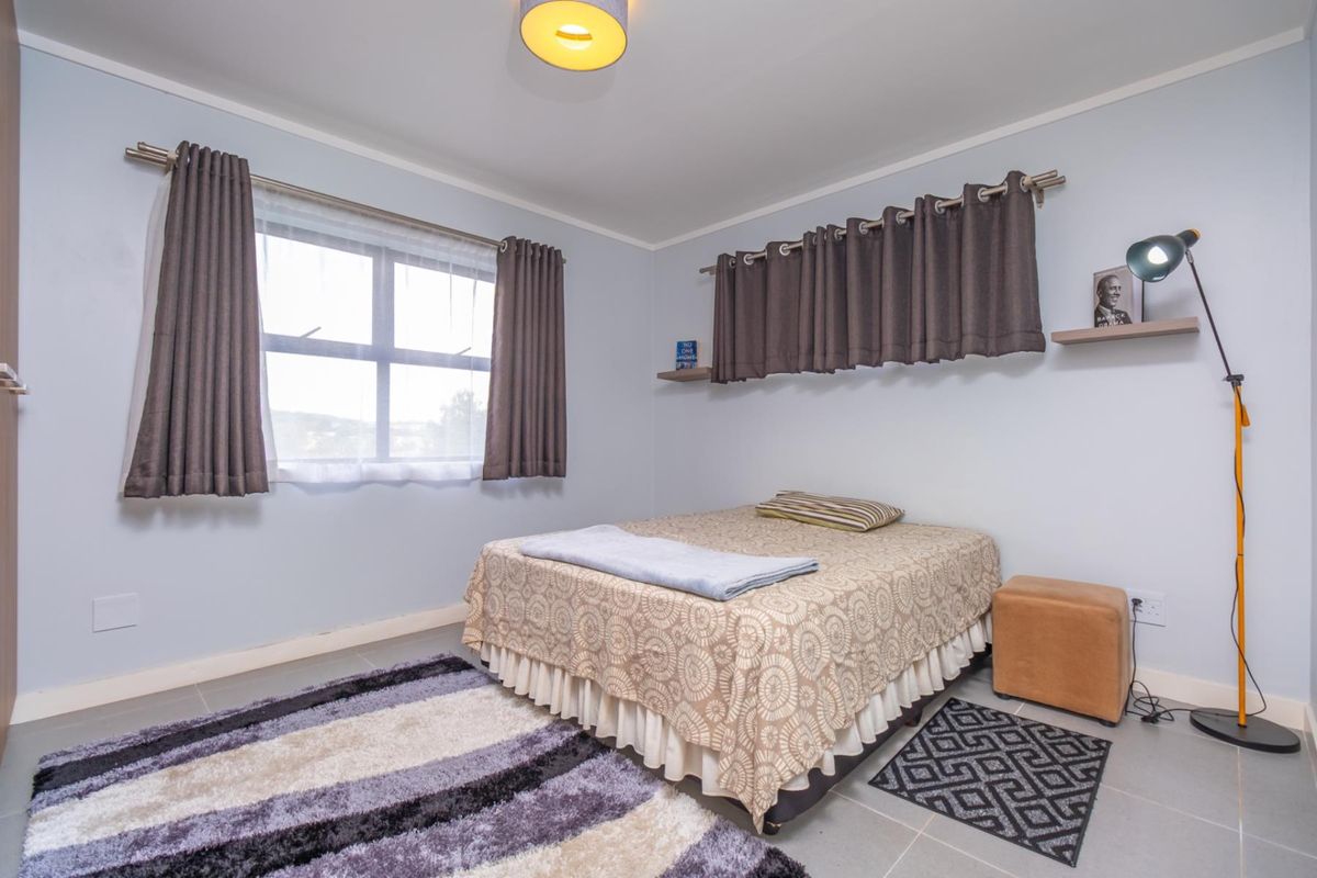 A well-lit bedroom featuring tiled flooring, neutral wall finishes, and a window with curtain rod fixtures.