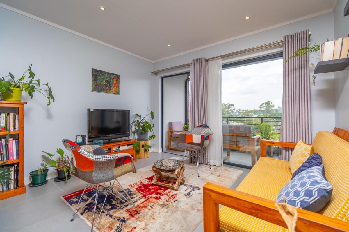 A bright living room featuring large sliding glass doors that open onto a private balcony, providing natural light and outdoor access.