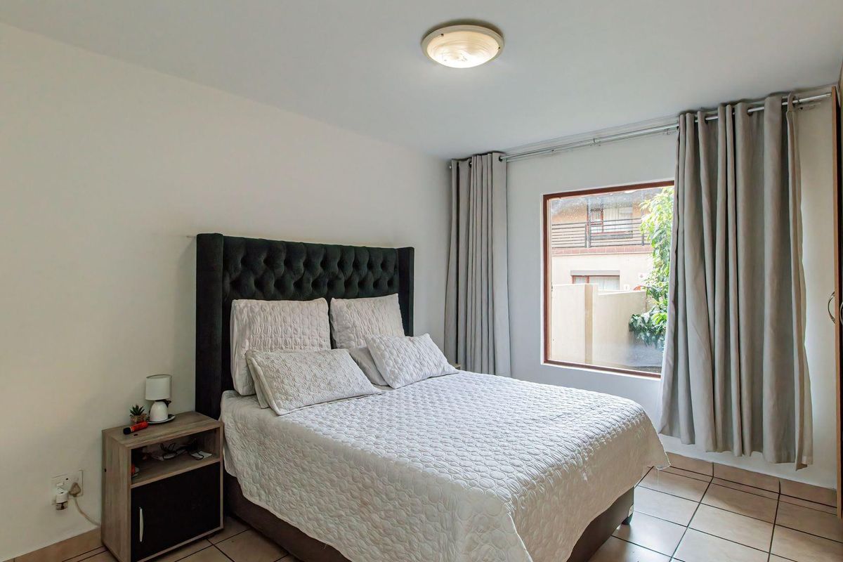 A bedroom featuring tiled flooring, a built-in wardrobe, and a window with curtain tracks.