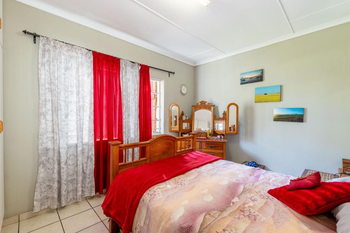 A functional bedroom featuring tiled flooring, large windows with curtain rods, and standard ceiling finishes.