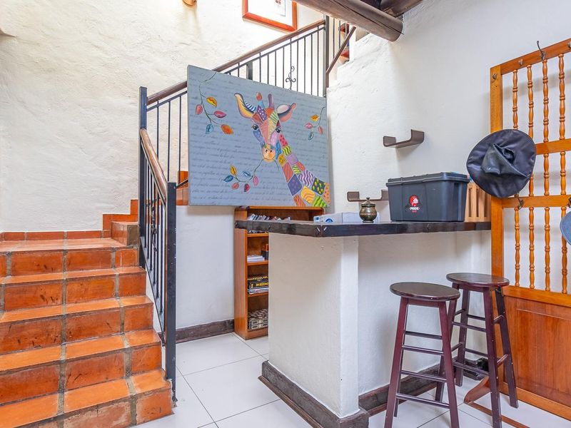 An entrance area featuring a terracotta tiled staircase with a wrought iron balustrade and a built-in bar counter.