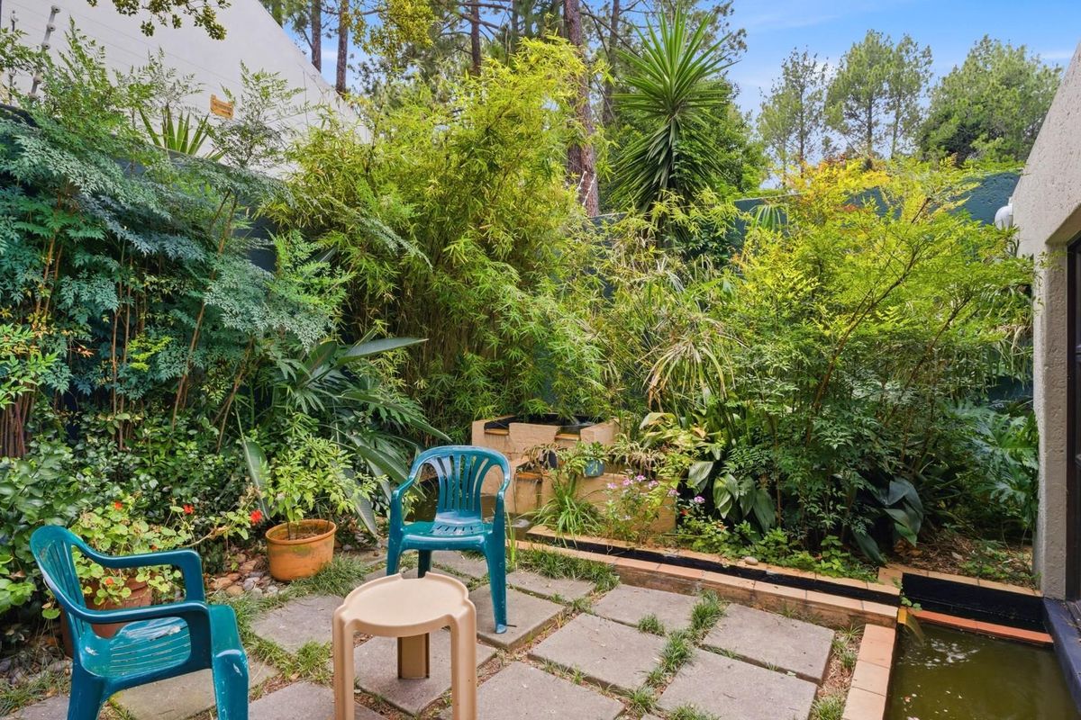 A private rear garden featuring paved patio area, established greenery, and a small built-in water feature, providing a secluded outdoor space.