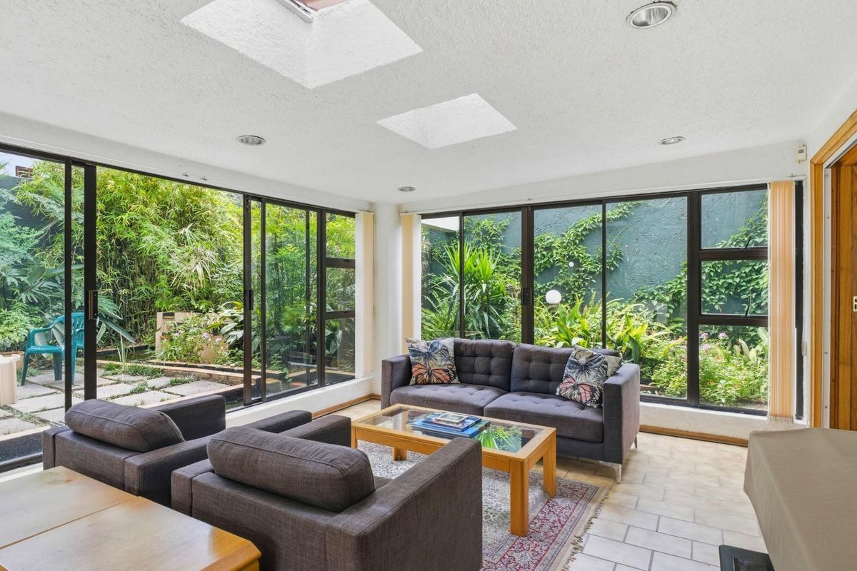 Bright living room featuring large floor-to-ceiling sliding glass doors, skylights, and direct access to a lush private garden.