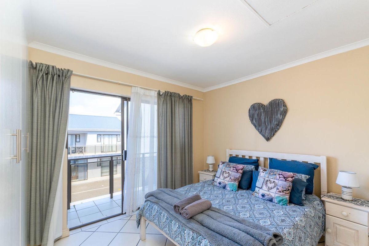 A bedroom featuring tiled flooring, built-in cupboards, and a sliding glass door providing access to a private balcony.