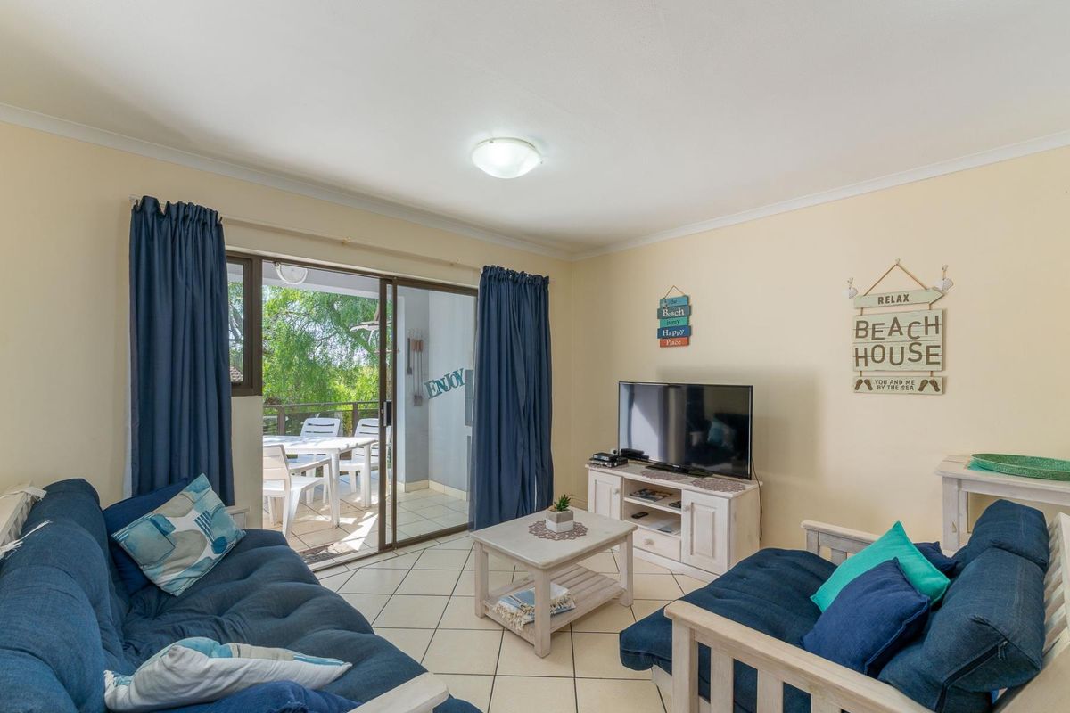 A bright living room featuring tiled flooring and sliding glass doors that open onto a private patio area.