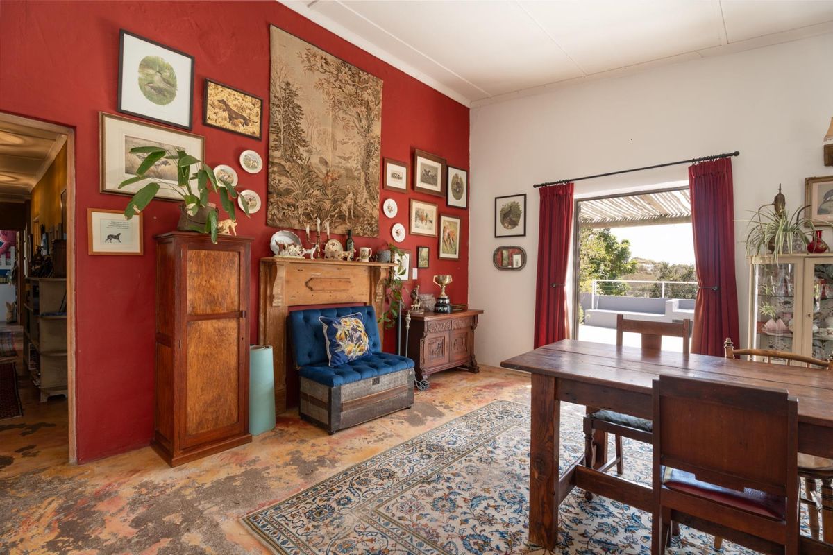 A living area featuring a prominent red accent wall, a decorative wooden fireplace mantel, and direct access to an outdoor patio.