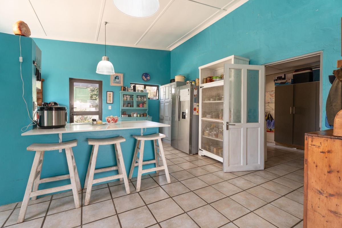 A functional kitchen featuring a breakfast bar, tiled flooring, and built-in cabinetry, with an adjacent pantry or utility area.