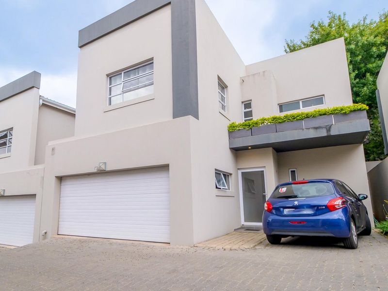 Modern double-storey townhouse featuring a clean architectural facade, automated double garage, and a private balcony with integrated planter boxes.