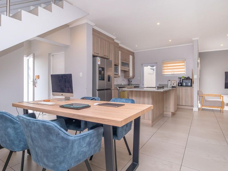Spacious open-plan living area featuring a modern kitchen with stone countertops, a central island, and tiled flooring, seamlessly connected to the dining space.