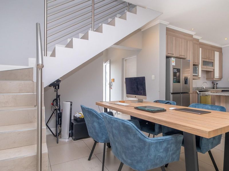 Open-plan living area featuring a modern staircase with stainless steel balustrade, tiled floors, and a well-appointed kitchen with granite countertops and integrated cabinetry.