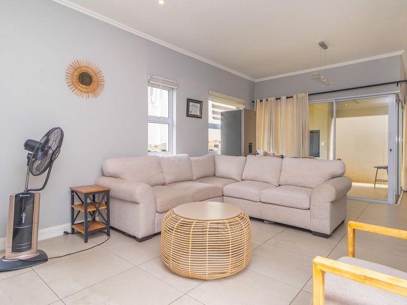 A bright and spacious living room featuring neutral tiled flooring, recessed lighting, and large sliding glass doors providing access to the outdoor area.