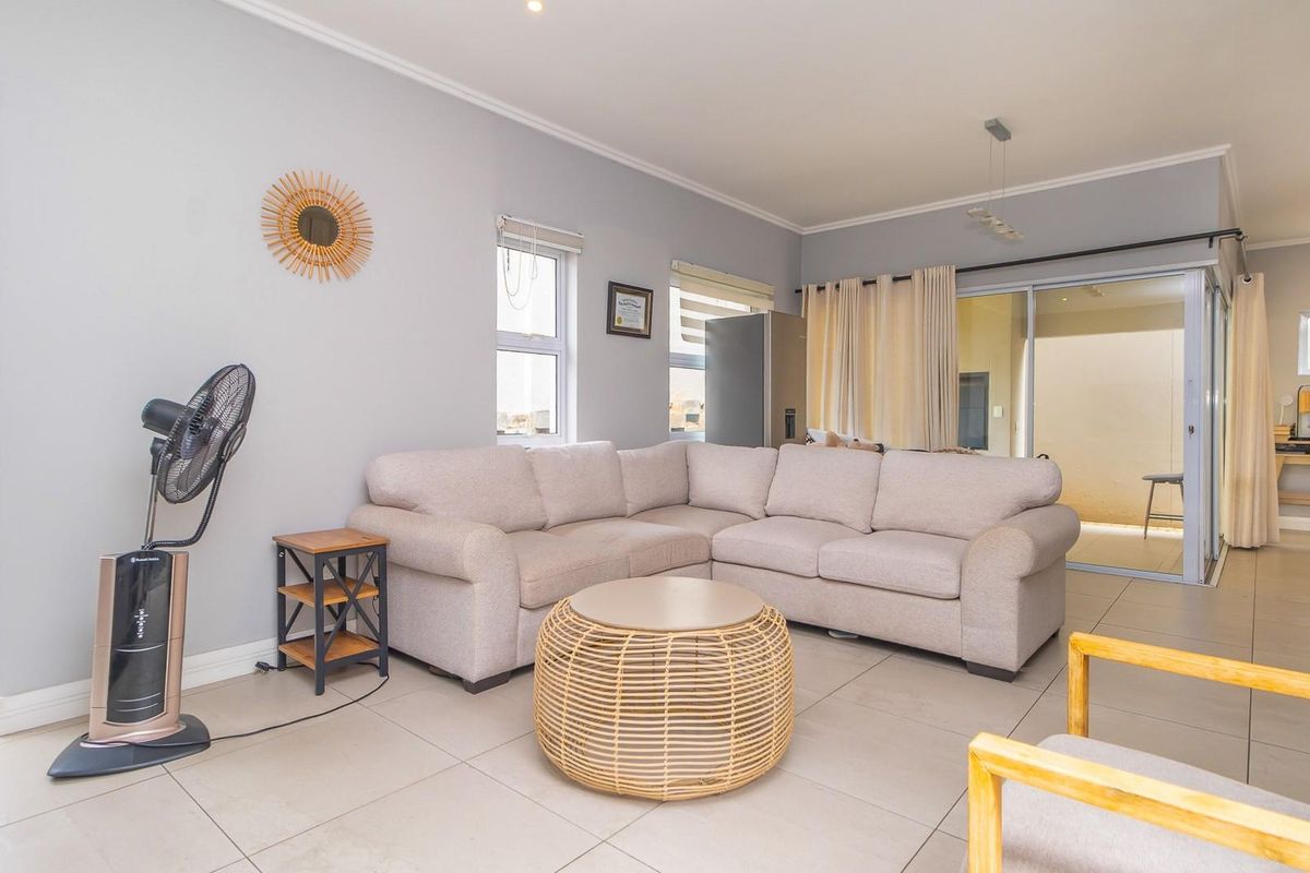 A bright and spacious living room featuring neutral tiled flooring, recessed lighting, and large sliding glass doors providing access to the outdoor area.