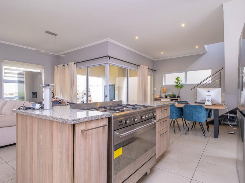 Spacious open-plan living area featuring a modern kitchen island with a gas stove, granite countertops, and seamless flow to the dining and lounge spaces.