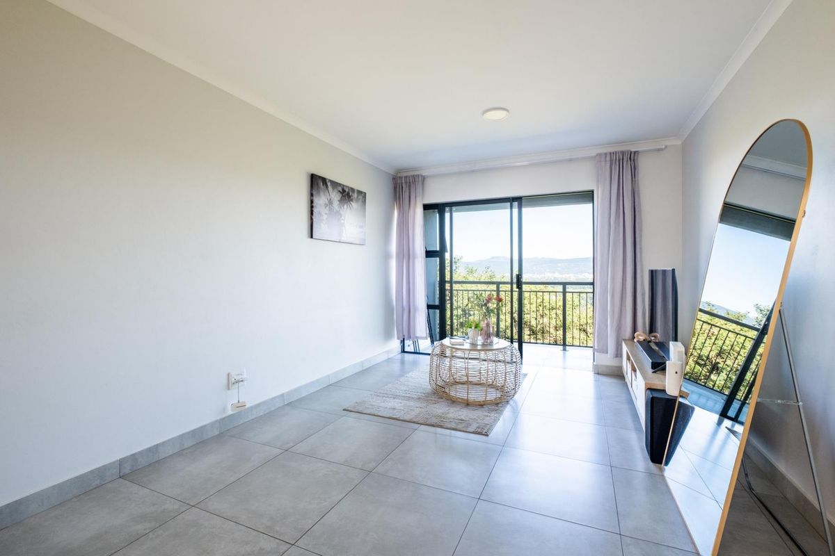 A bright living room featuring large sliding glass doors that open onto a balcony, offering natural light and scenic views.