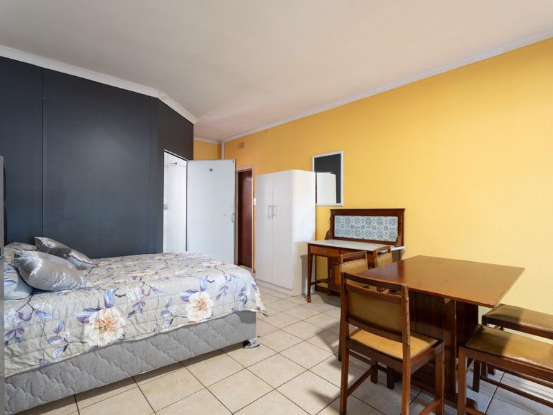 Open-plan studio apartment featuring tiled flooring and a combined living and sleeping area with contrasting wall colors.