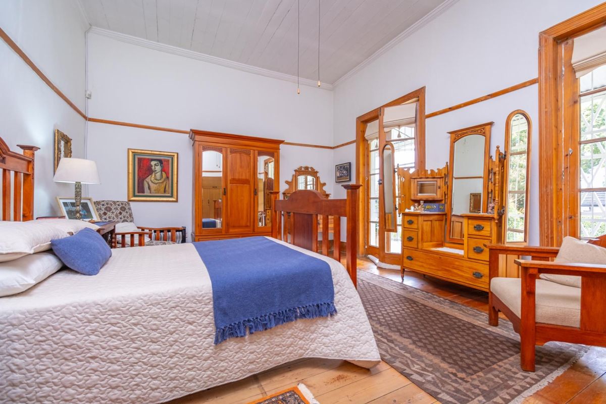 Spacious bedroom featuring high ceilings, timber flooring, and direct access to the garden through glass-paneled doors.