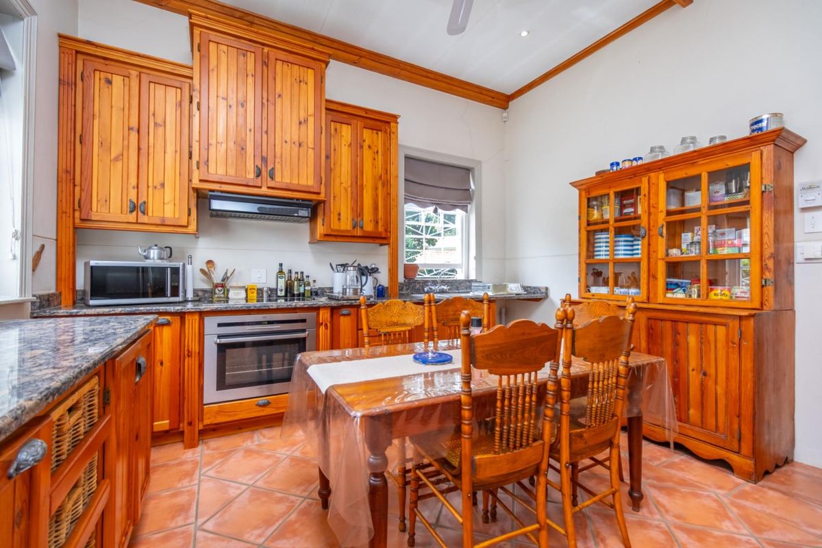 A traditional kitchen featuring solid timber cabinetry, granite countertops, tiled flooring, and an integrated oven with extractor fan.