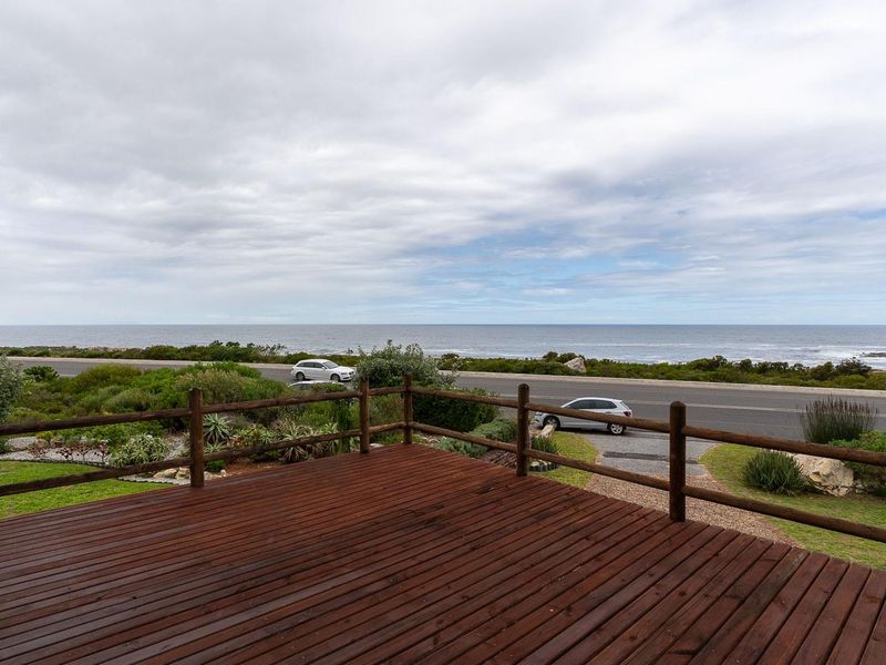 A spacious elevated timber deck offering expansive coastal and ocean views, featuring a rustic wooden railing and direct outdoor access.