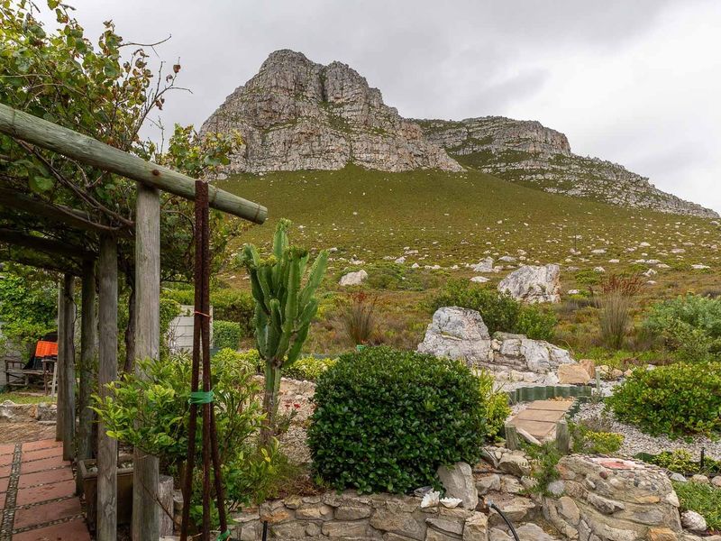 A scenic garden area featuring a timber pergola and stone retaining wall, offering expansive views of the mountain landscape.