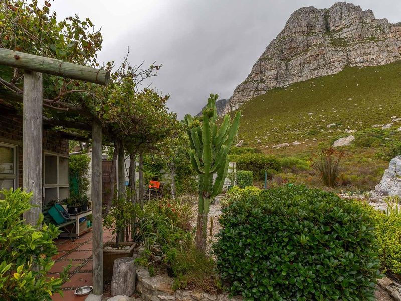 A covered patio area featuring a timber pergola, overlooking a landscaped garden with mountain views.
