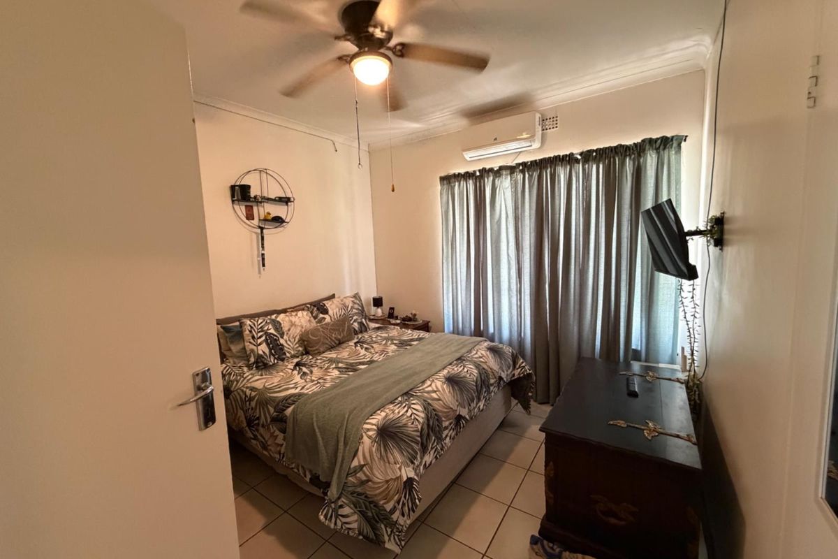 A bedroom featuring tiled flooring, a ceiling fan, and a wall-mounted air conditioning unit.