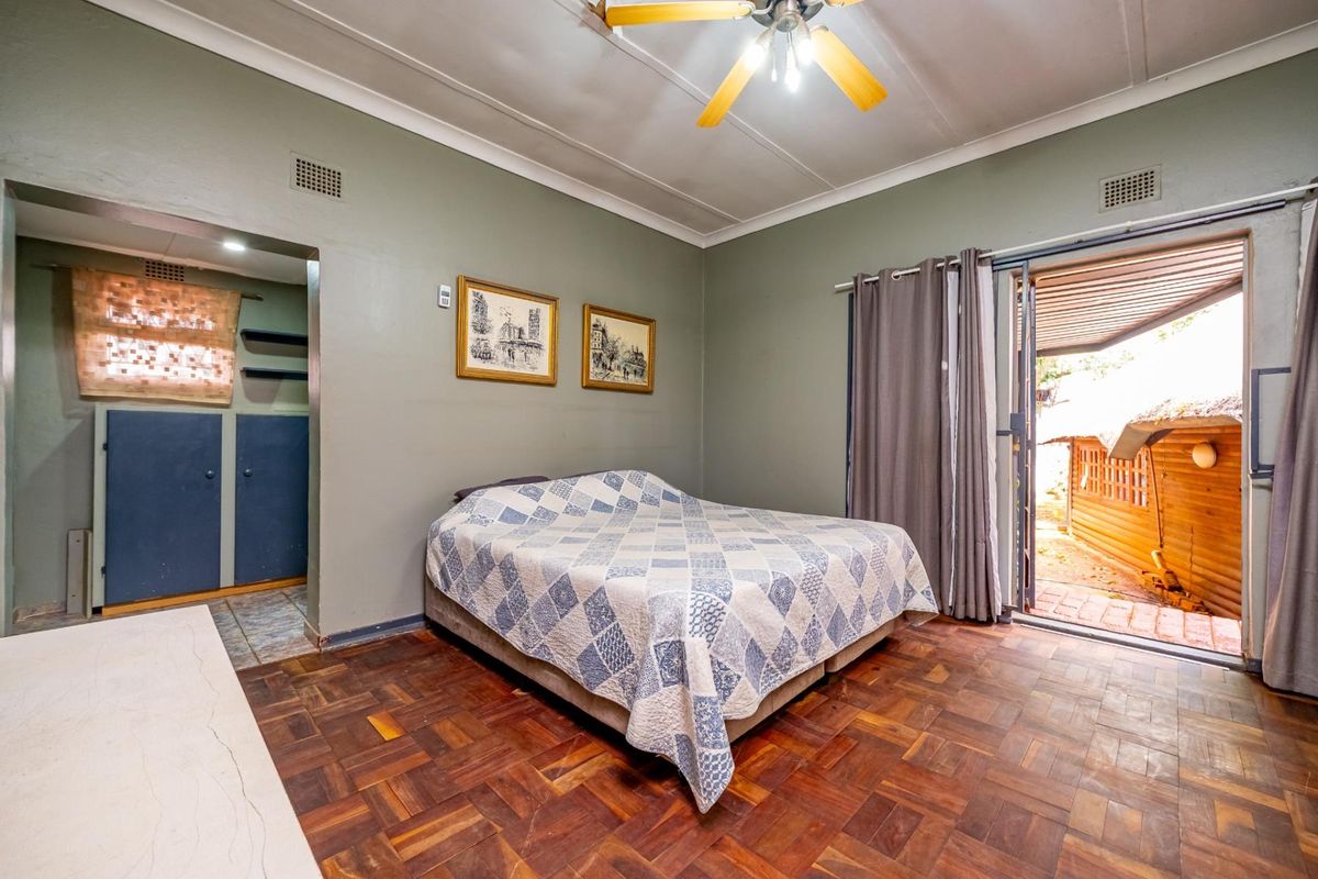 A bedroom featuring parquet flooring, a ceiling fan, and direct access to an outdoor patio area through a sliding glass door.