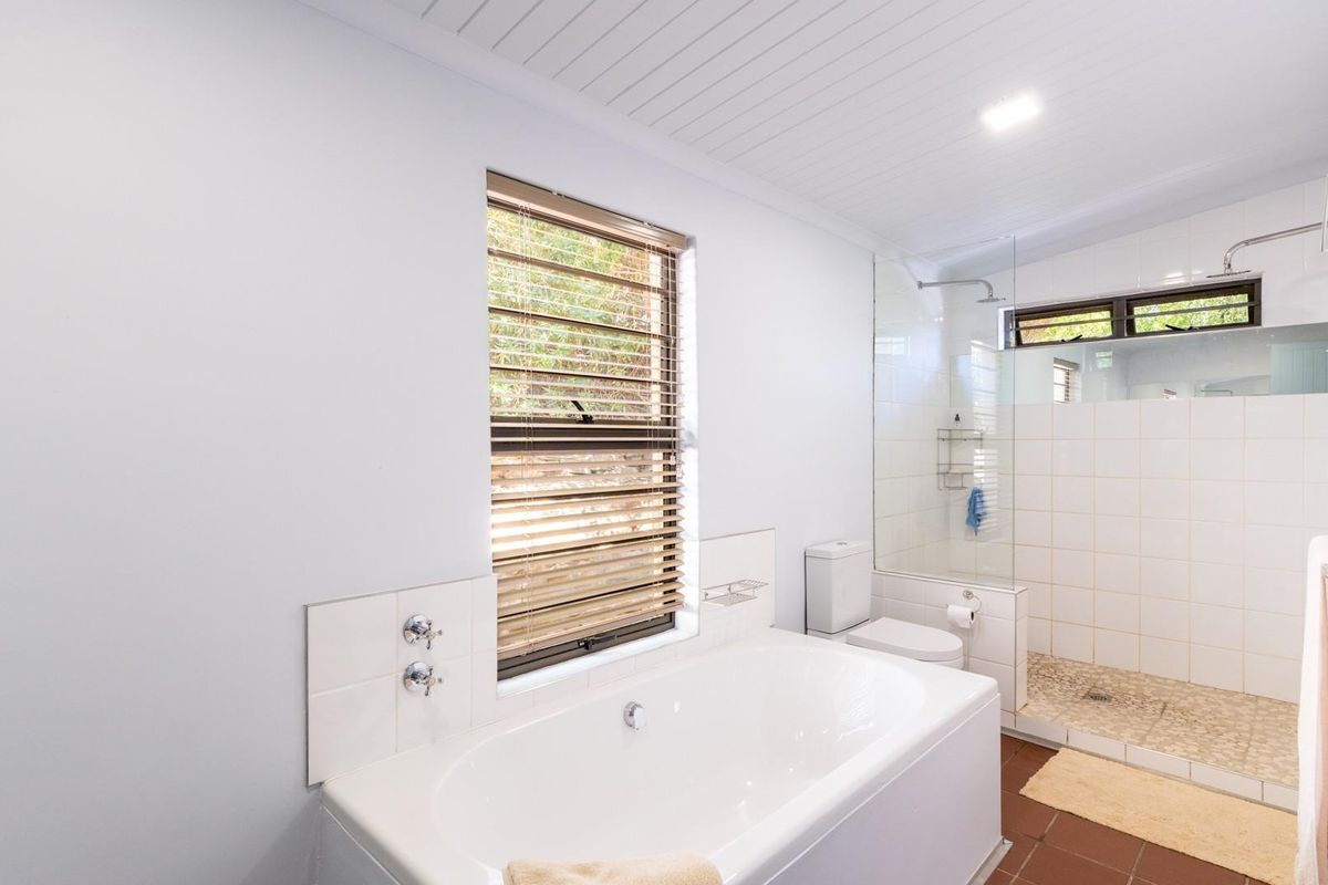 A bright, modern bathroom featuring a built-in bathtub, a separate walk-in shower with glass enclosure, and tiled flooring.