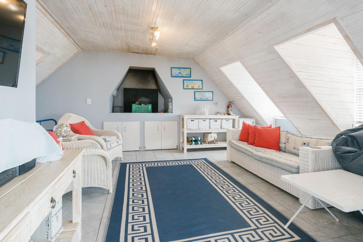 Attic-style living room featuring a built-in fireplace, vaulted timber-clad ceiling, and tiled flooring, offering a cozy and versatile entertainment space.