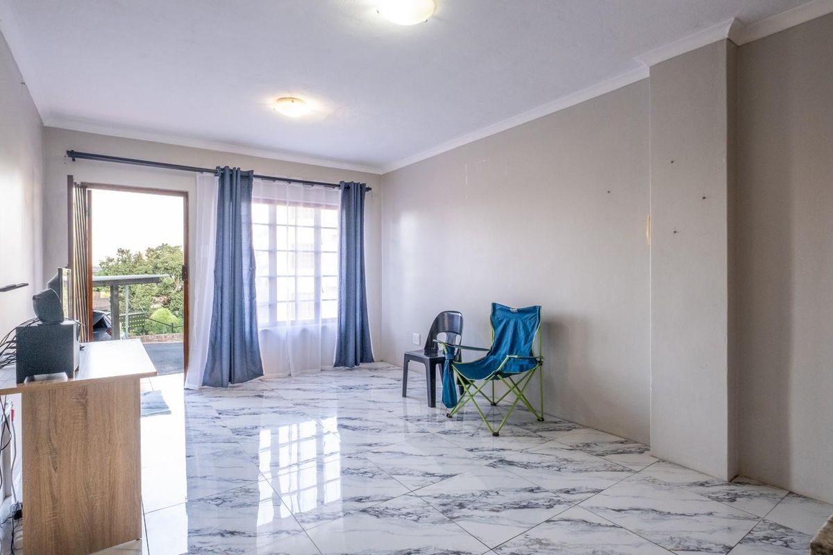 Spacious living area featuring polished marble-look floor tiles, neutral wall finishes, and direct access to an outdoor balcony area.