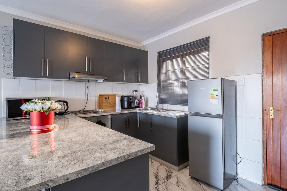 Modern kitchen featuring dark grey cabinetry, granite-look countertops, tiled backsplash, and marble-effect floor tiles.