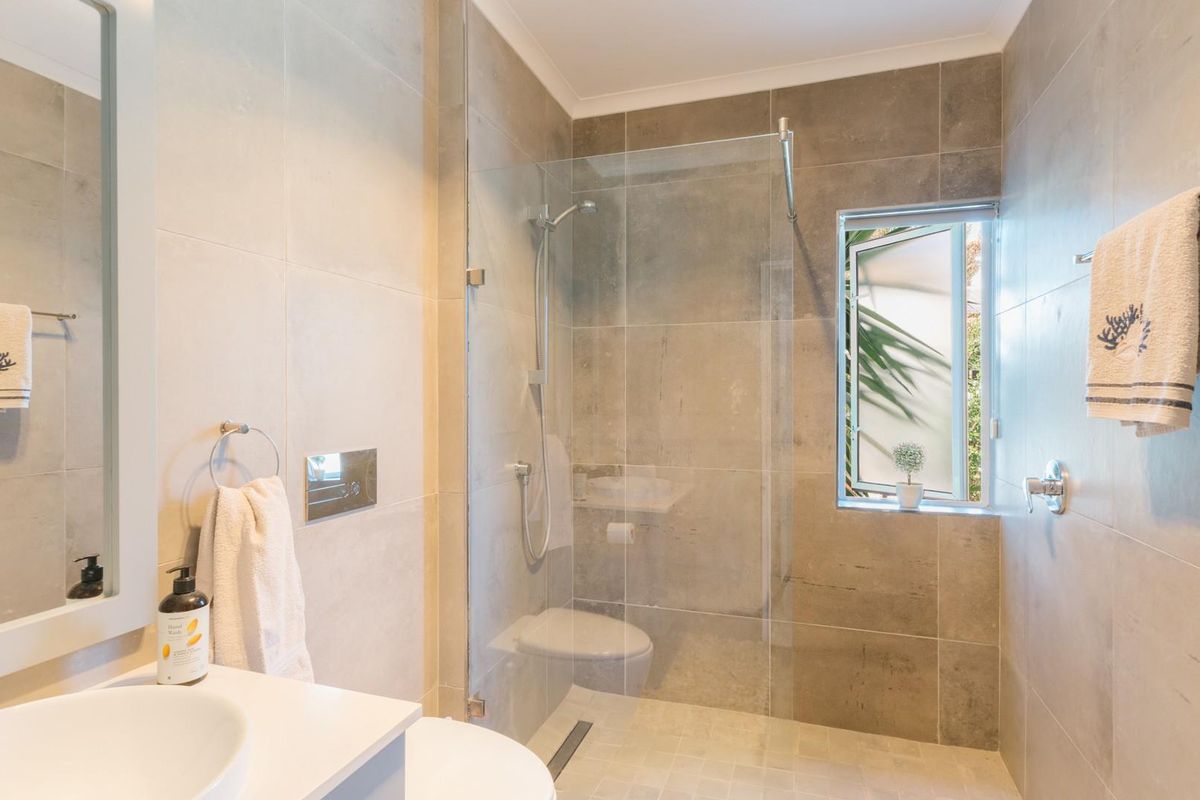 Modern bathroom featuring large format grey wall tiles, a frameless glass walk-in shower, and a contemporary vanity with a vessel sink.