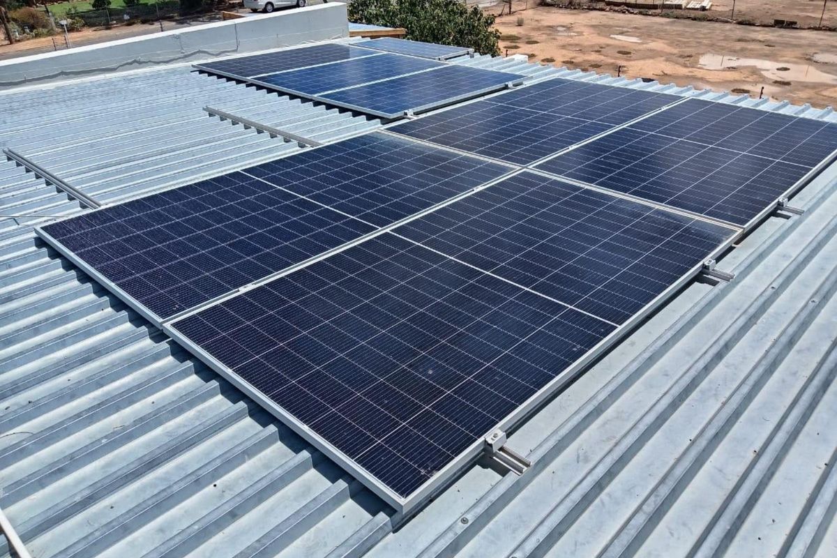 A high-angle view of a corrugated metal roof featuring a mounted solar panel array for renewable energy generation.