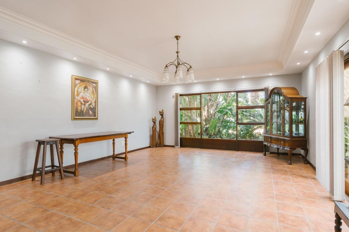 Spacious living area featuring large timber-framed windows, recessed ceiling lighting, and tiled flooring, offering a bright and open space for relaxation.